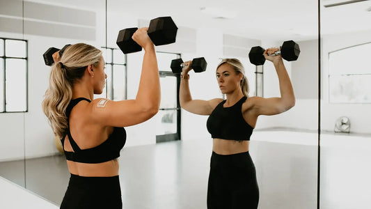 Image of a woman lifting dumbbells while wearing a DrySee dressing on her shoulder.
