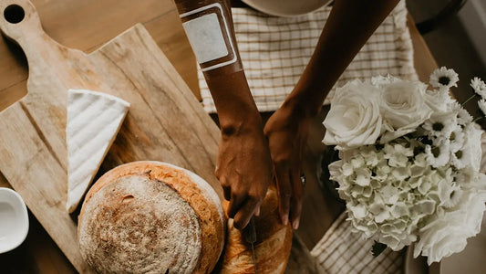 Image of a person with fresh loaves of bread on a cutting board. One arm sports a DrySee dressing.