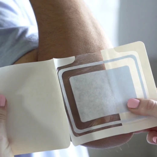 a doctor applies a DrySee bandage to a person's arm